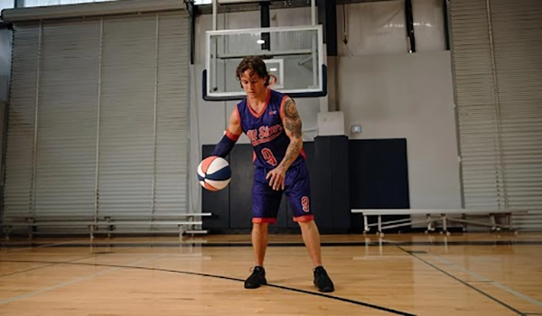 Basketball player in purple uniform dribbling on an indoor court