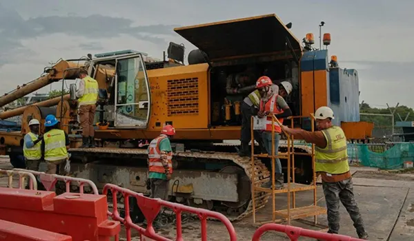 Construction workers repairing the engine of a heavy machinery excavator