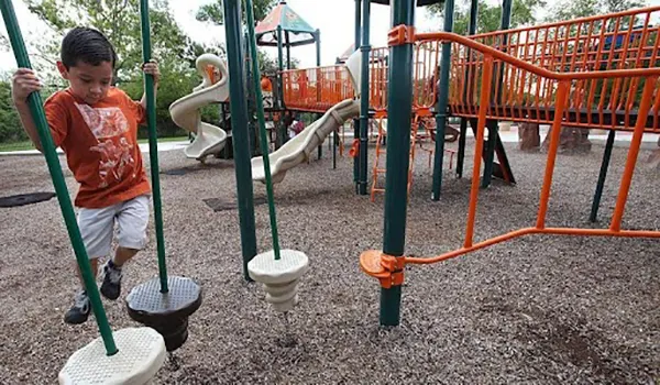 Young boy balancing on a playground stepping stone bridge